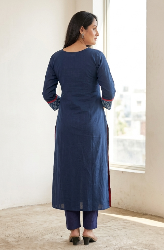Back view of a model standing indoors, wearing a solid dark blue straight kurta and matching pants.
