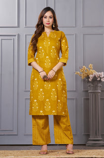 Front full length view of a model wearing an ochre yellow straight fit floral print cotton kurta set with coordinating chevron pants and a printed dupatta