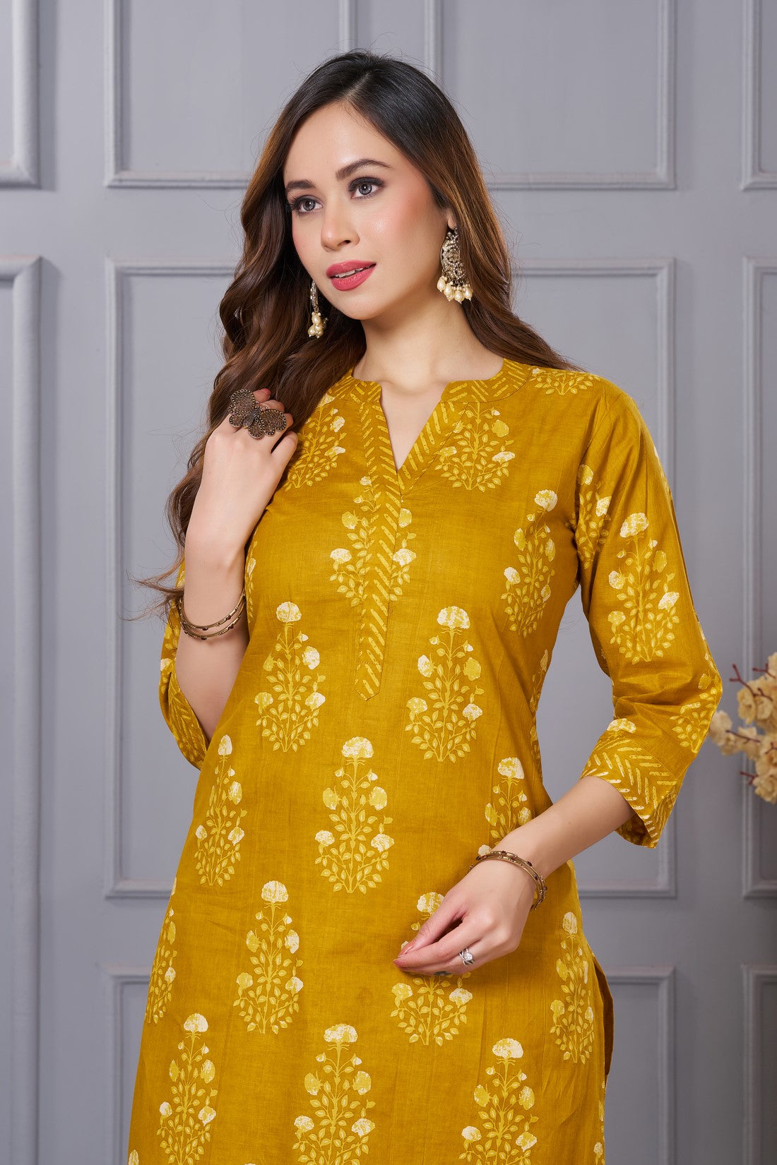 Close up view of the V neckline design showcasing white lace inserts and contrasting border details on the ochre yellow floral printed cotton kurta
