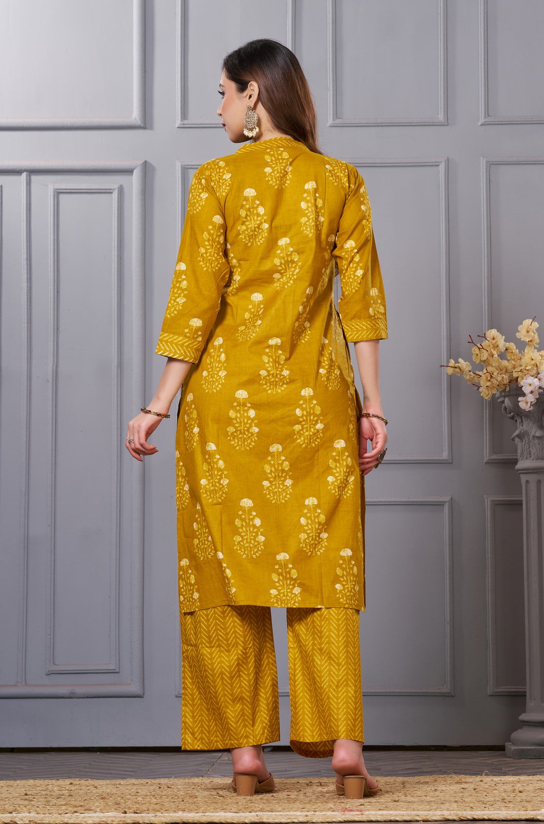 Back view of the ochre yellow straight fit floral cotton kurta set showcasing the fit of the trousers and the falling pattern of the printed dupatta