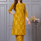Side profile view of a model in the ochre yellow floral printed cotton salwar suit showcasing the elegant side slit and chevron trousers