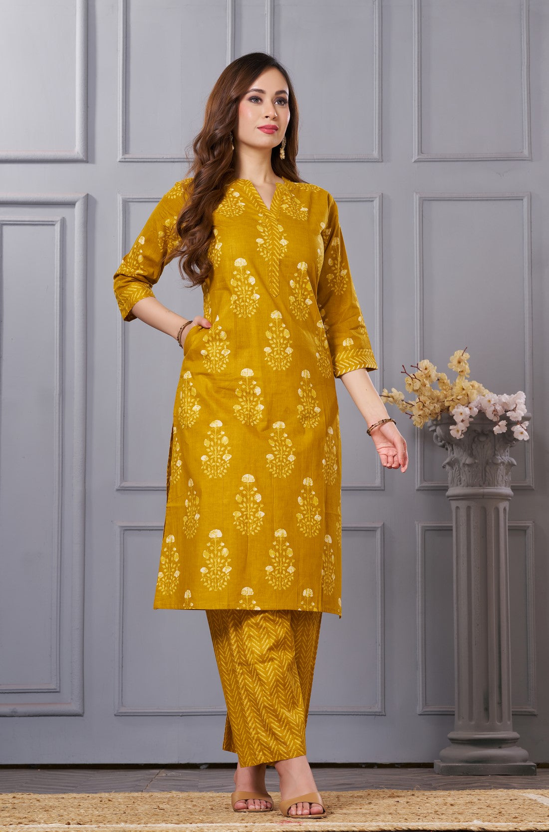 Side profile view of a model in the ochre yellow floral printed cotton salwar suit showcasing the elegant side slit and chevron trousers