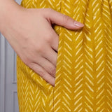 Close up view of the functional side utility pocket stitched seamlessly into a teal floral cotton straight kurta, showing a hand resting inside the pocket over contrasting purple chevron print trousers.
