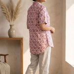 Back profile of a women's blush pink hand block print cotton shirt with short sleeves and curved hem.