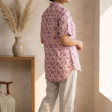 Back profile of a women's blush pink hand block print cotton shirt with short sleeves and curved hem.