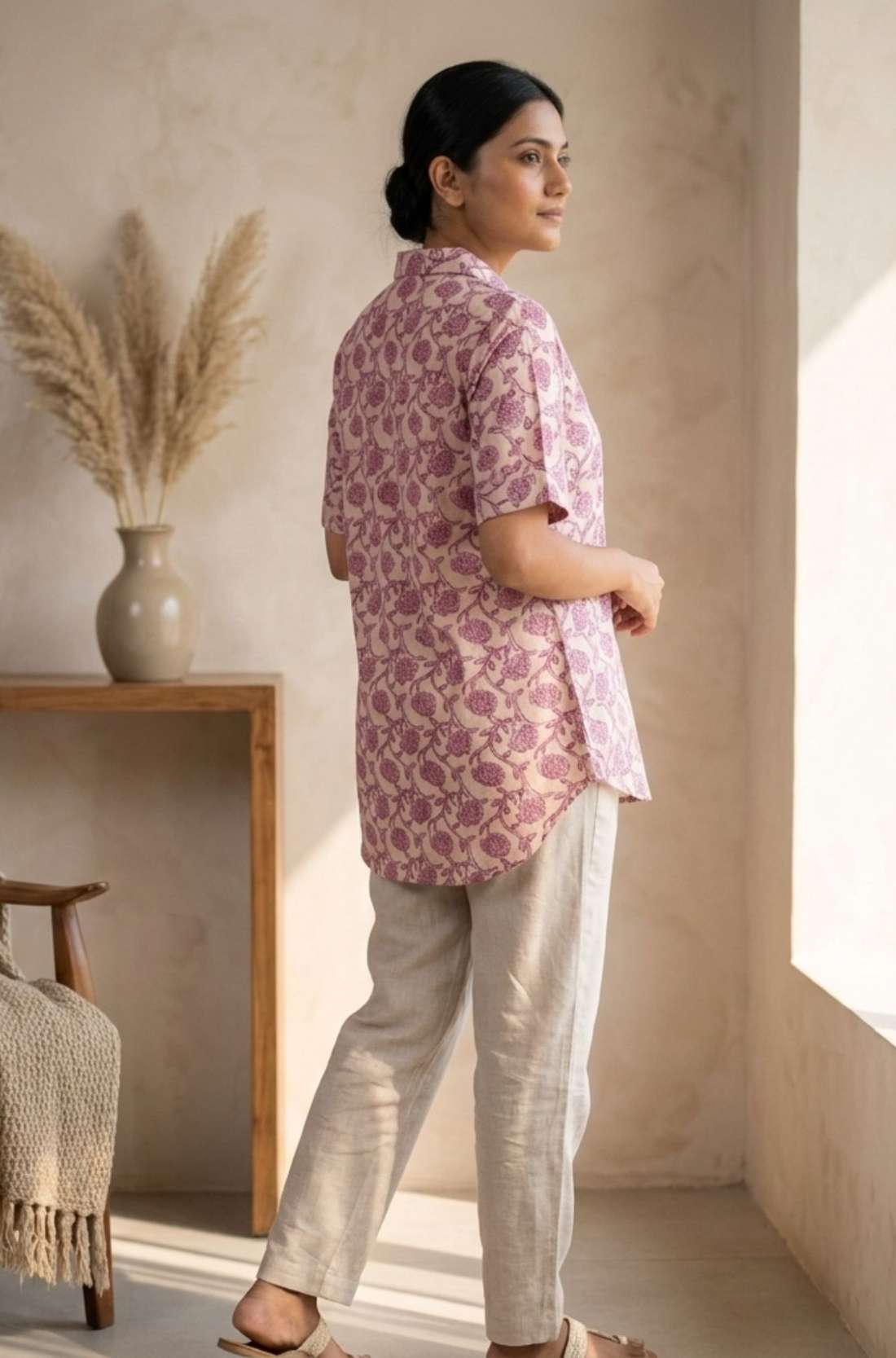 Back profile of a women's blush pink hand block print cotton shirt with short sleeves and curved hem.