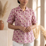 Front view of a women's blush pink floral hand block print cotton shirt with wooden buttons and short sleeves.