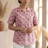 Front view of a women's blush pink floral hand block print cotton shirt with wooden buttons and short sleeves.