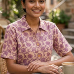 Women's blush pink floral hand block print cotton shirt styled casually while seated at an outdoor café.