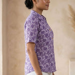 Side profile of a women's lavender floral block print cotton shirt paired with white trousers.