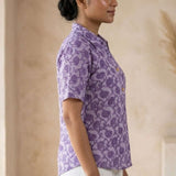 Side profile of a women's lavender floral block print cotton shirt paired with white trousers.