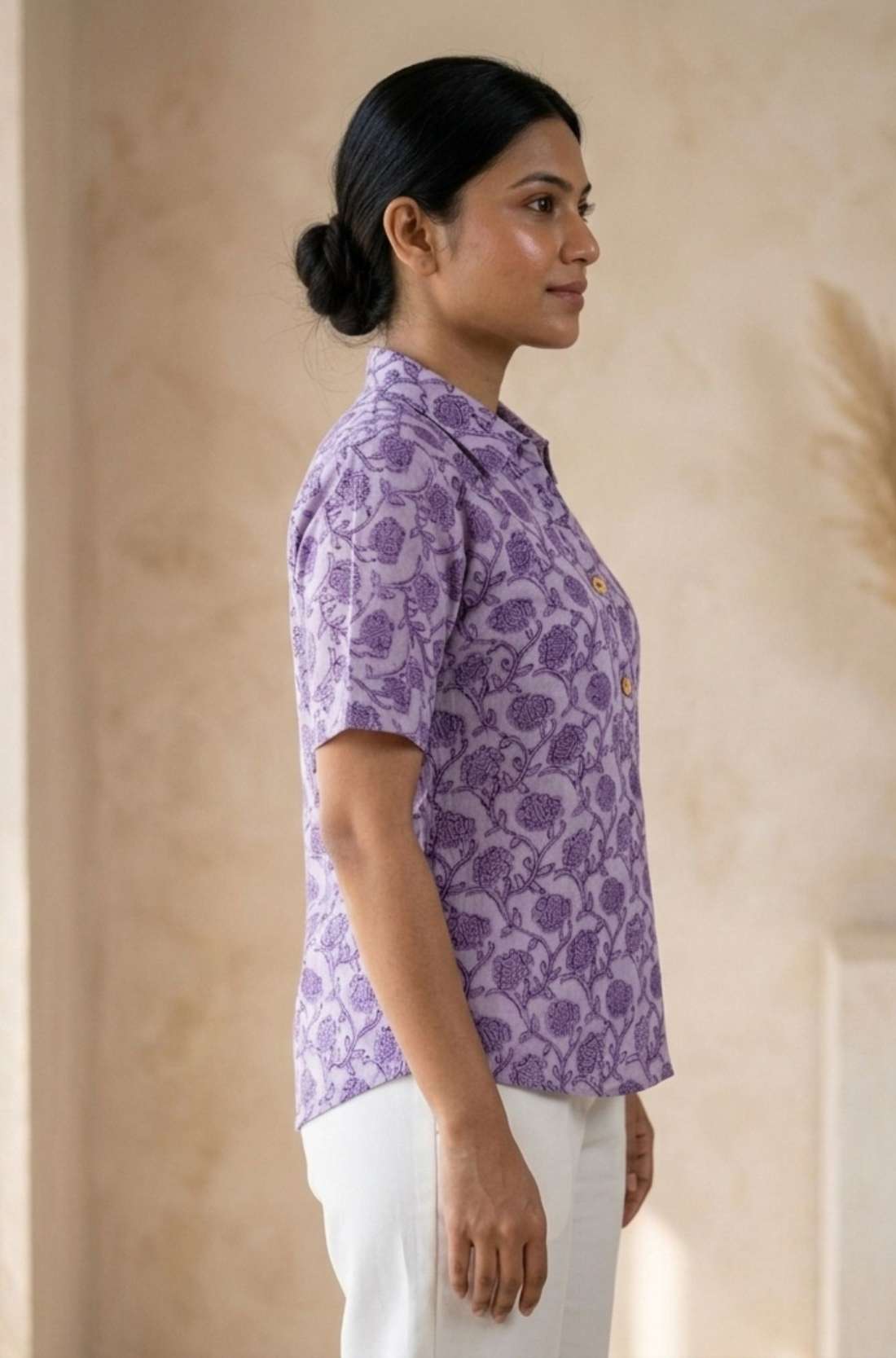 Side profile of a women's lavender floral block print cotton shirt paired with white trousers.
