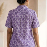 Back view of a women's lavender floral block print cotton shirt with short sleeves and curved hem.
