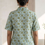 Back View
Back view of a women's mint green block print cotton shirt featuring short sleeves and curved hem.