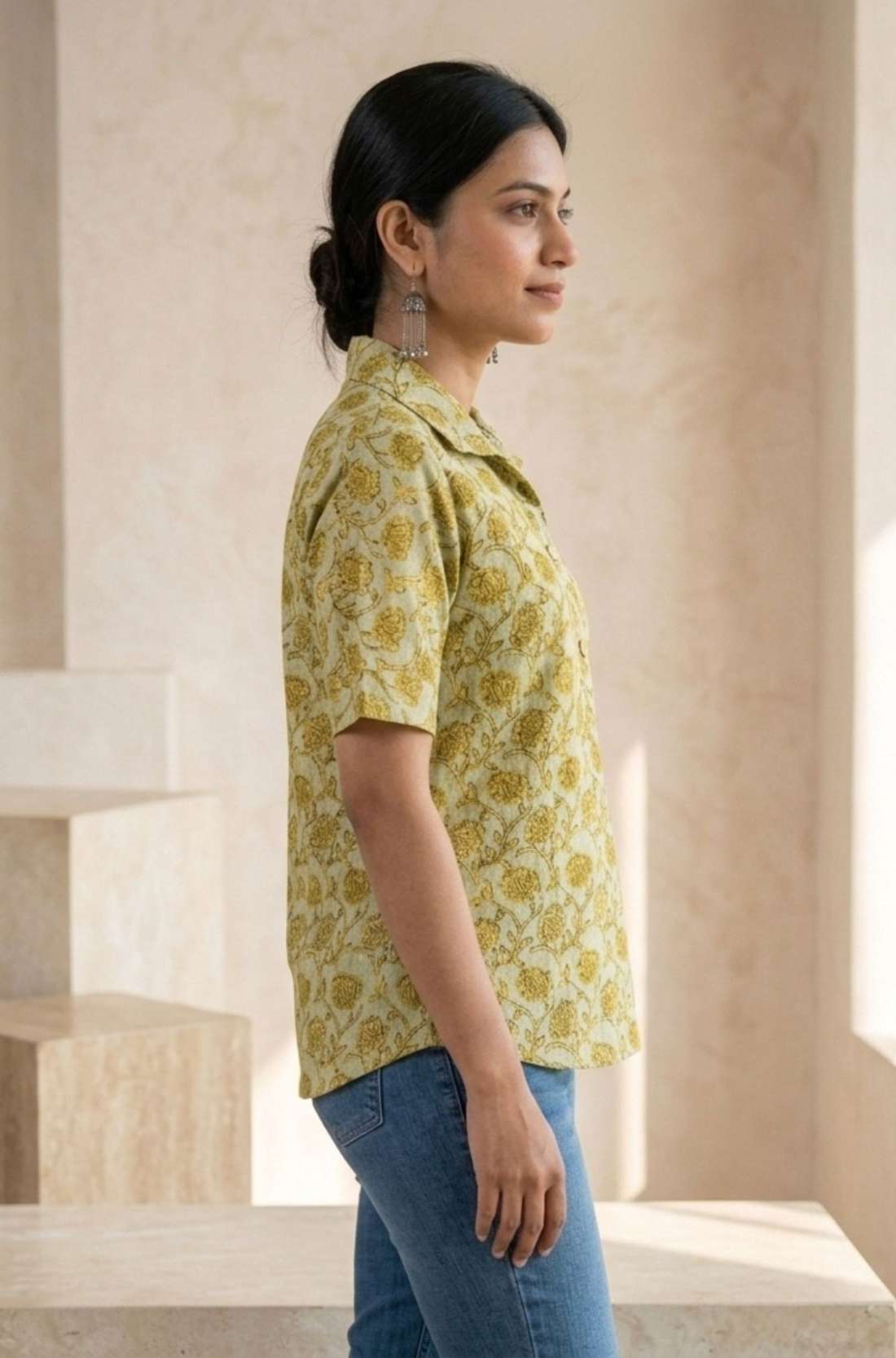 Side profile of a women's yellow floral block print cotton shirt with relaxed fit and collared neckline.