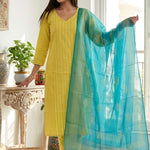 A smiling woman sitting on a white chair wearing a stylish yellow pure cotton thread embroidered kurta set with a matching printed dupatta