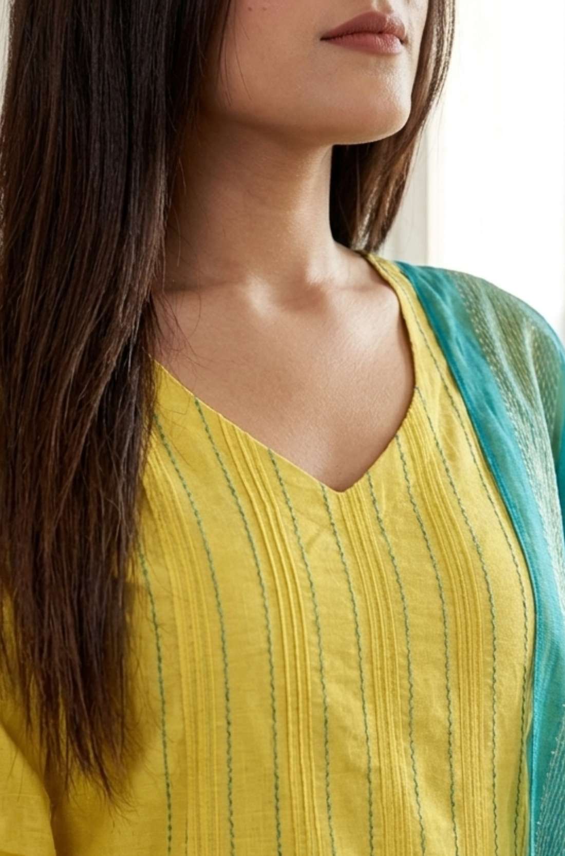 Close up shot of the V neckline showing the vertical pink thread embroidery lines and fine stitch work on the yellow cotton kurta