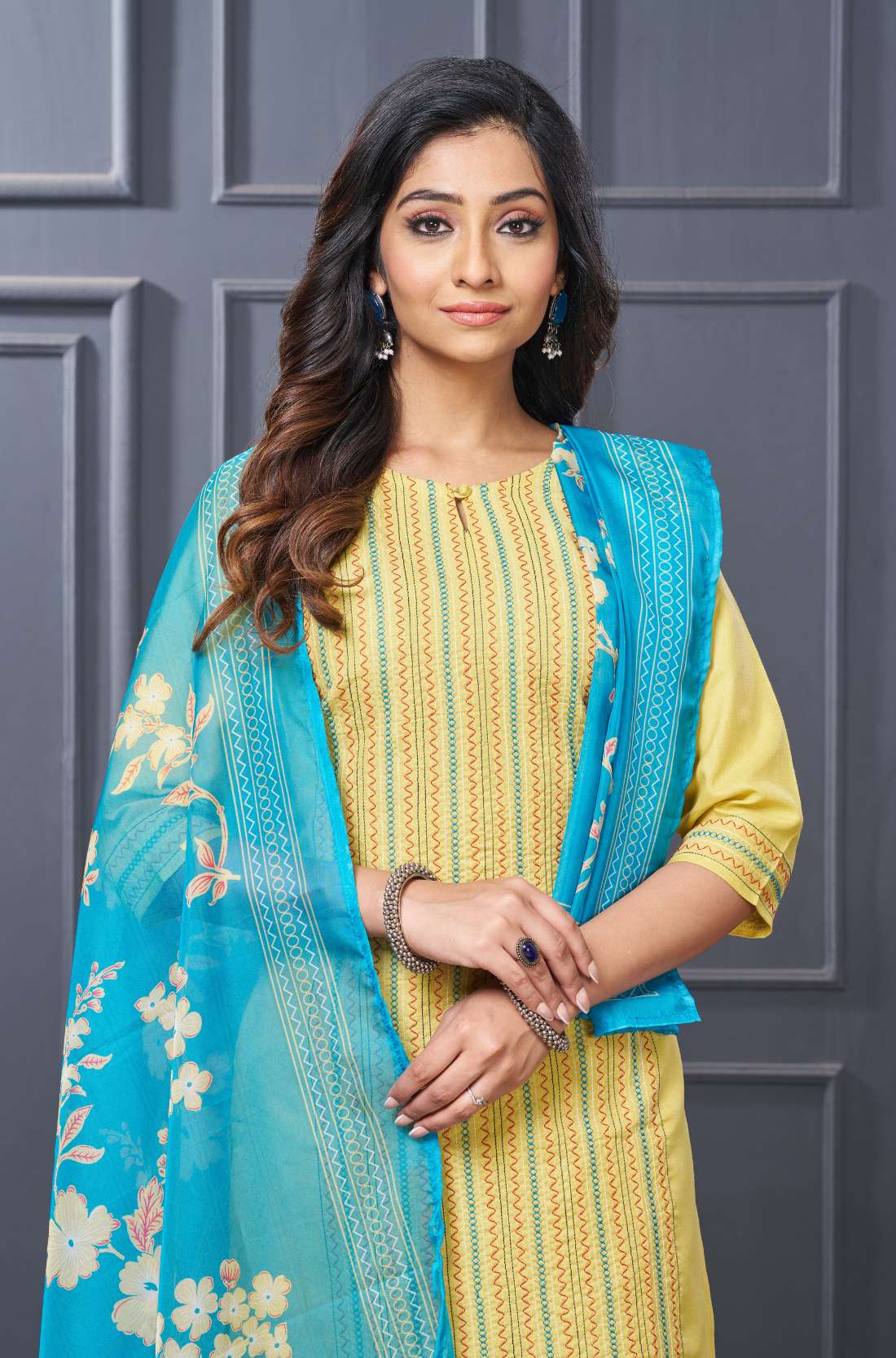 Close up view of the intricate front yoke design showcasing detailed multicolor floral thread embroidery alongside fine vertical pintucks on a premium yellow cotton kurta set
