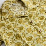 Flat lay of a yellow hand block print cotton shirt featuring floral print, collar, and wooden button placket.